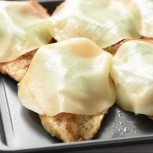 Prosciutto, basil and provolone are placed on top of chicken breasts.