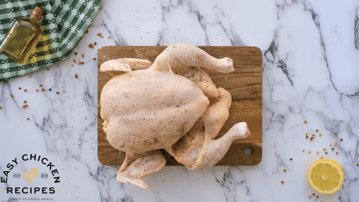 A chicken on a cutting board with lemons and spices.