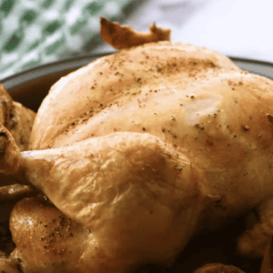 A whole roasted chicken is in a baking dish.