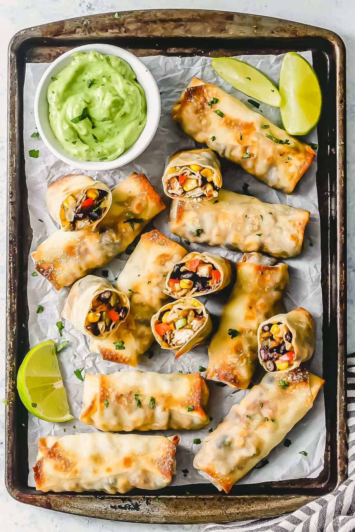 Baked Chicken Egg Rolls with creamy avocado sauce on sheet pan