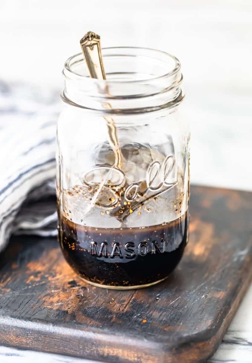 a mason jar partially-filled with balsamic chicken marinade, with a spoon dipped inside