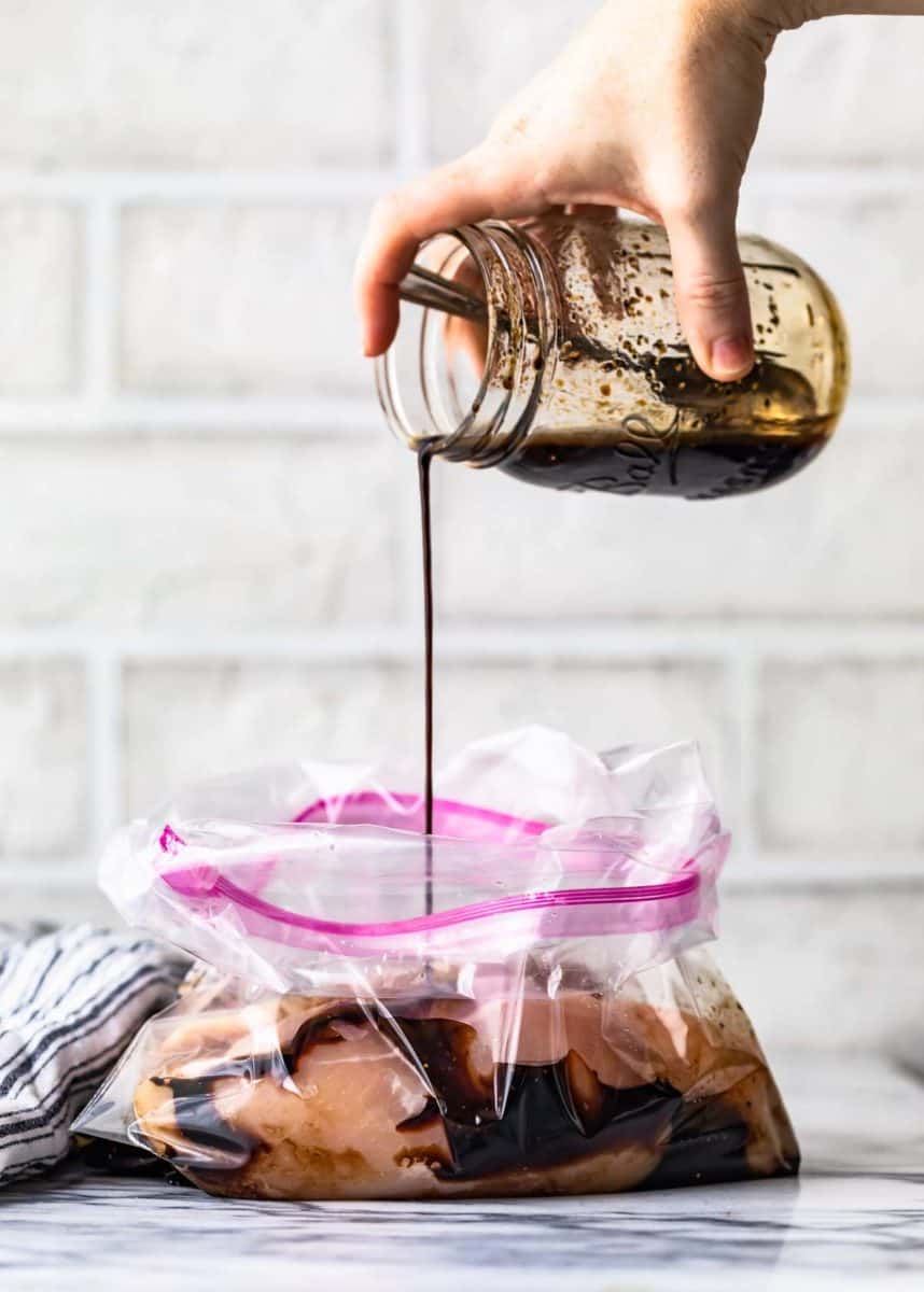 pouring balsamic marinade into a resealable bag of chicken breasts