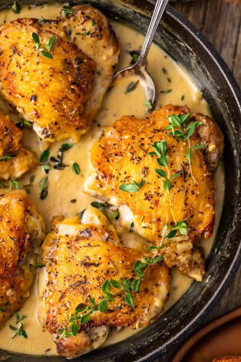 close up on a skillet of chicken thighs in a creamy dijon sauce