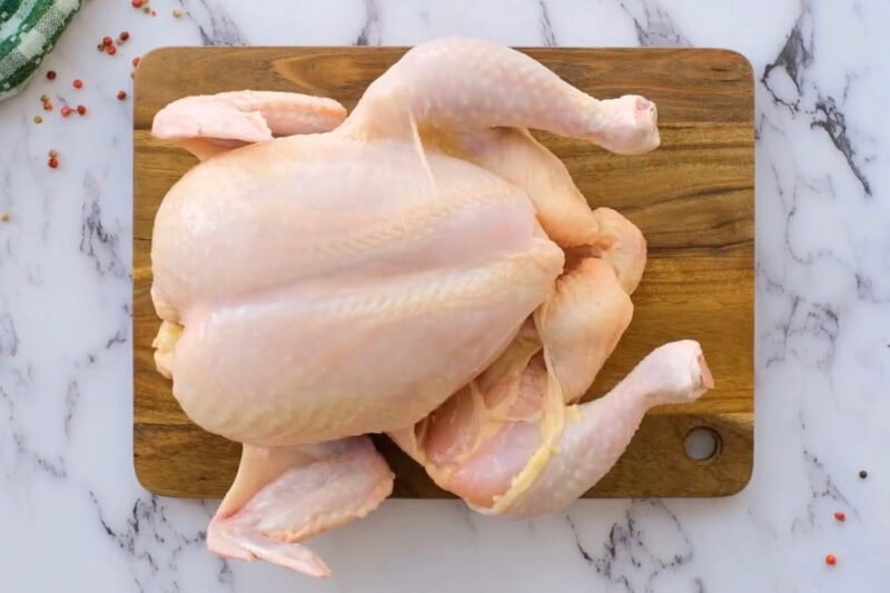a raw whole chicken on a cutting board.
