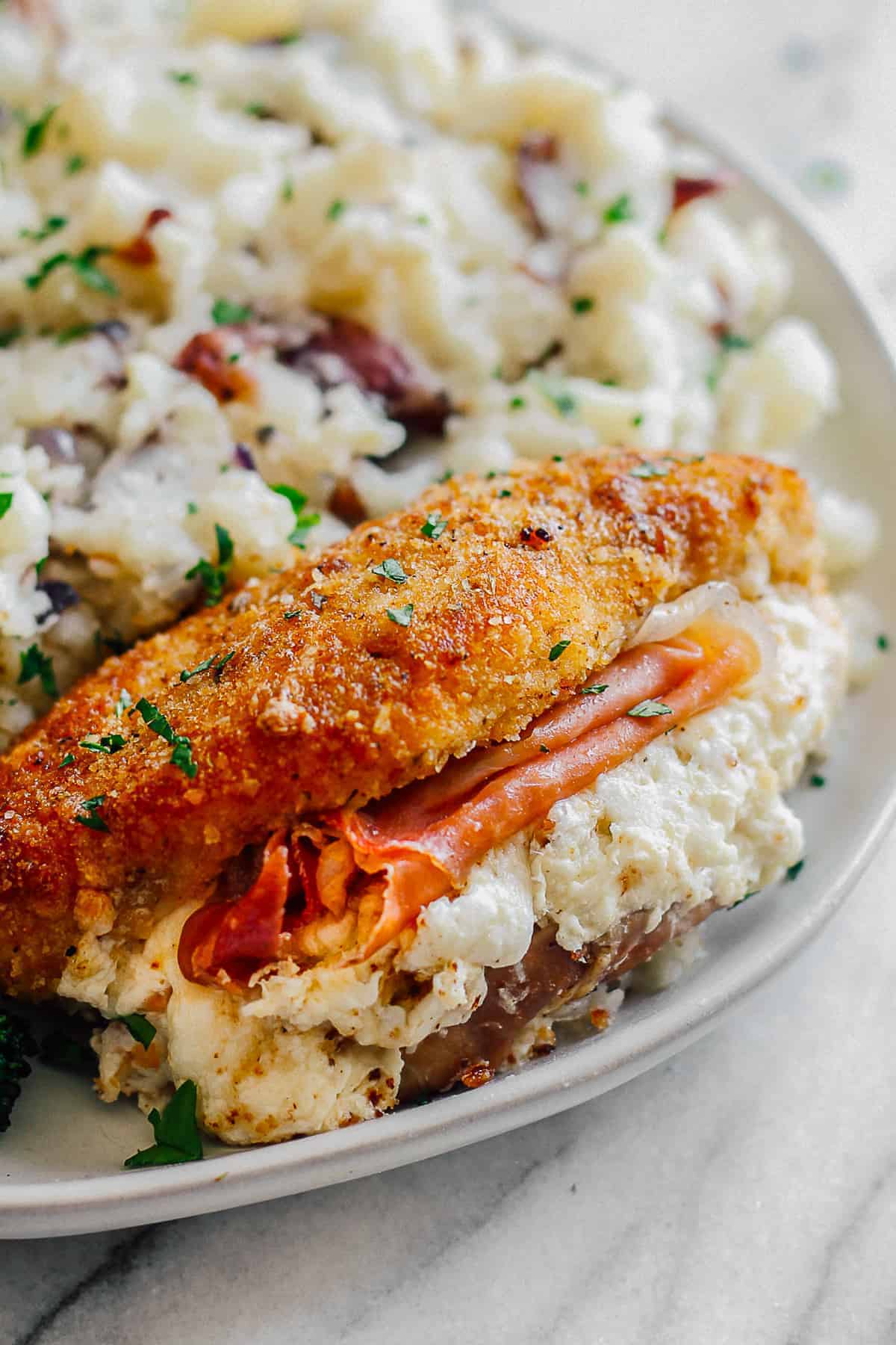 up close image of breaded chicken stuffed with prosciutto and cheese
