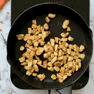 Small pieces of chicken are cooking in a skillet.
