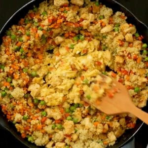scrambling eggs in the center of quinoa chicken fried rice.