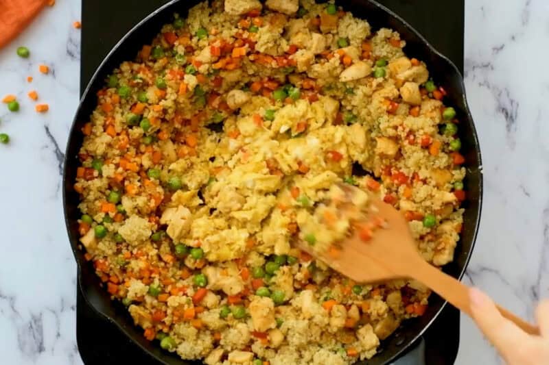 scrambling eggs in the center of quinoa chicken fried rice.