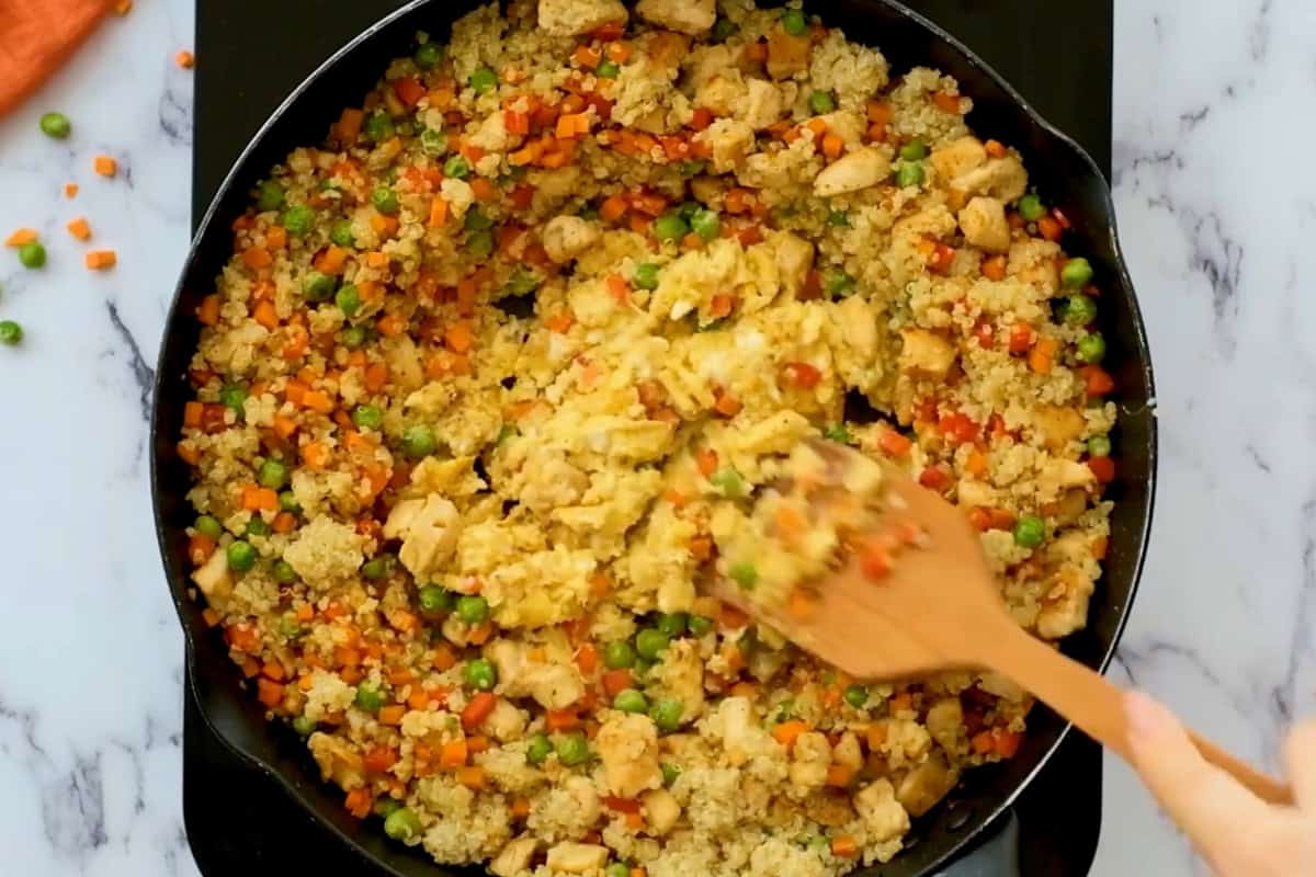 scrambling eggs in the center of quinoa chicken fried rice.