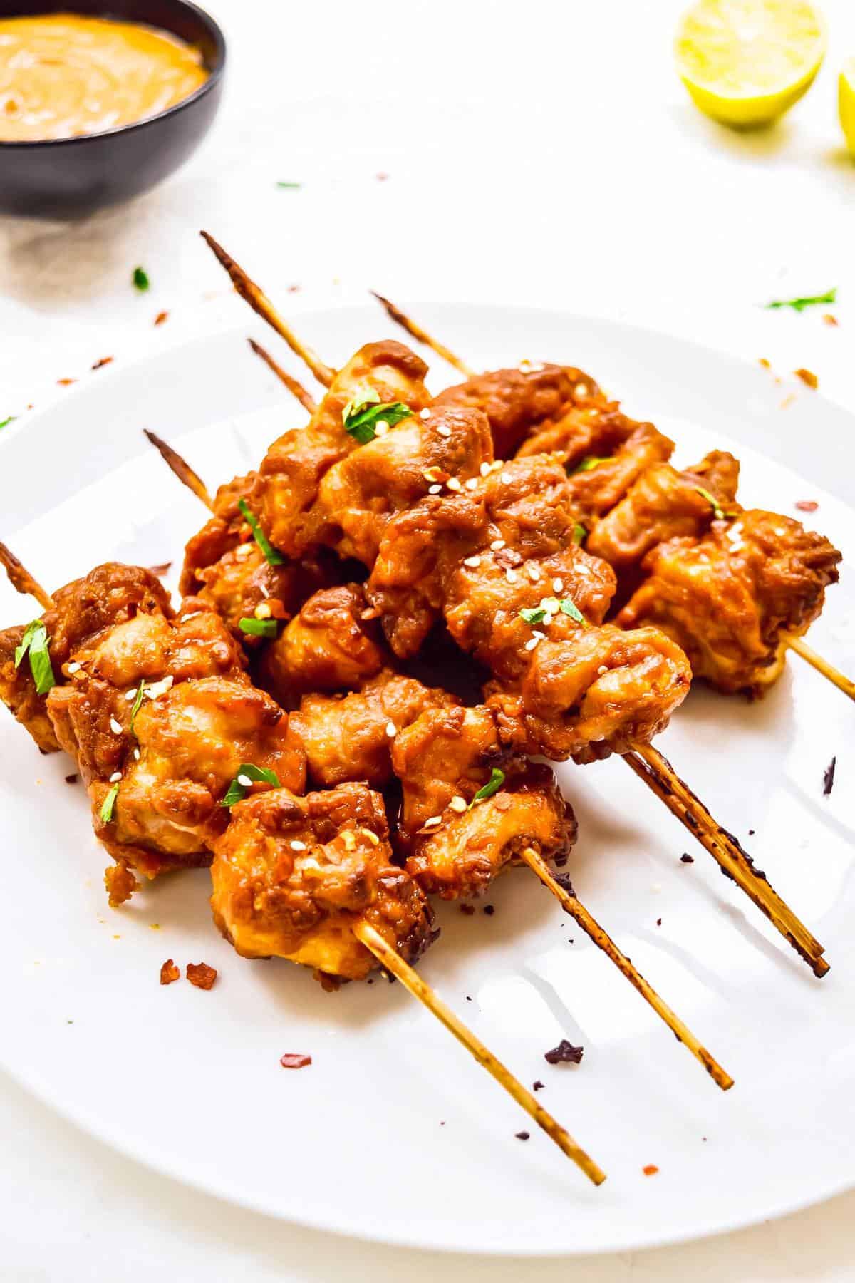 chicken satay skewers on a plate stacked