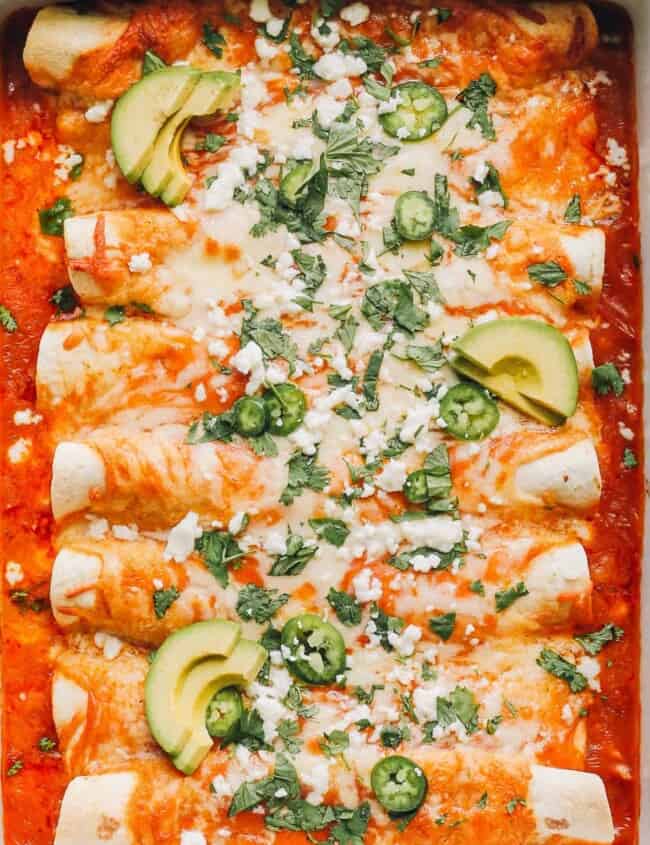 up close image of easy chicken enchiladas garnished with sour cream and cilantro