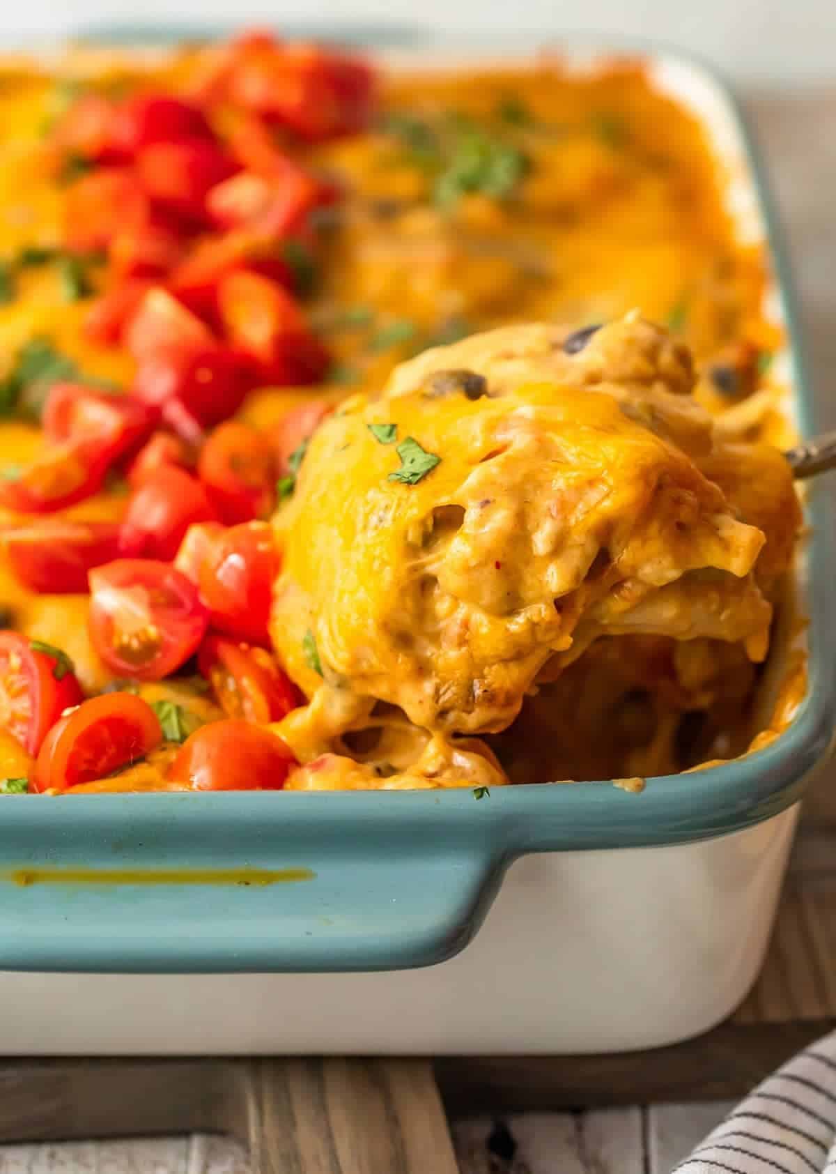 spooning out cheesy chicken casserole with tomatoes