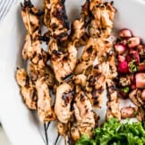 Grilled chicken kebabs on a large white serving plate