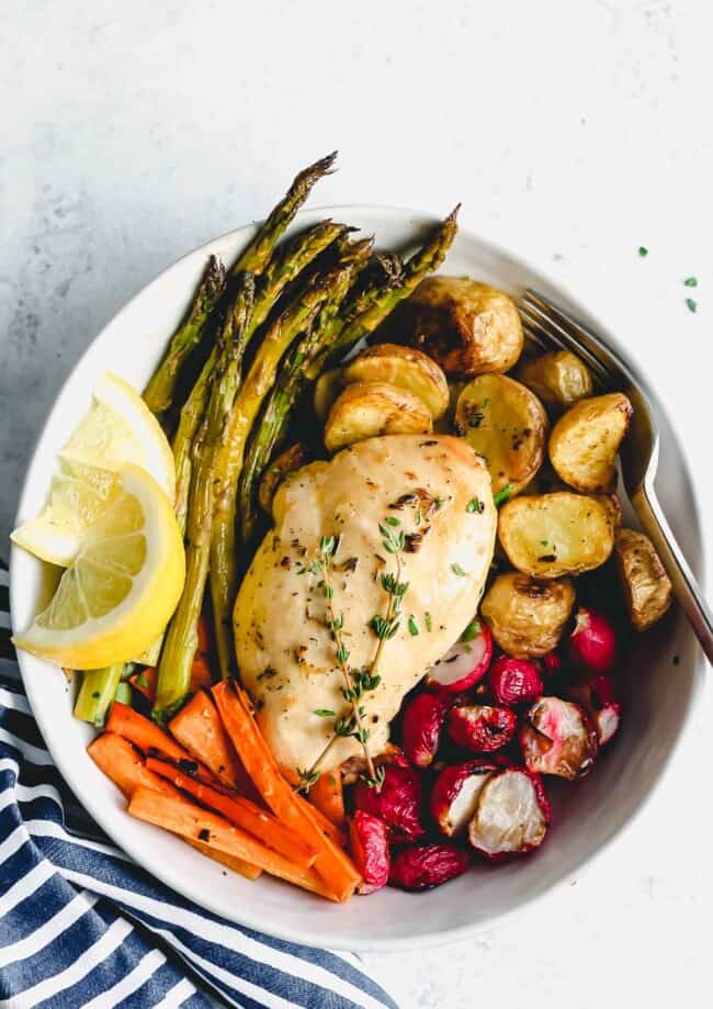 Cooked herb chicken in a bowl with roasted vegetables