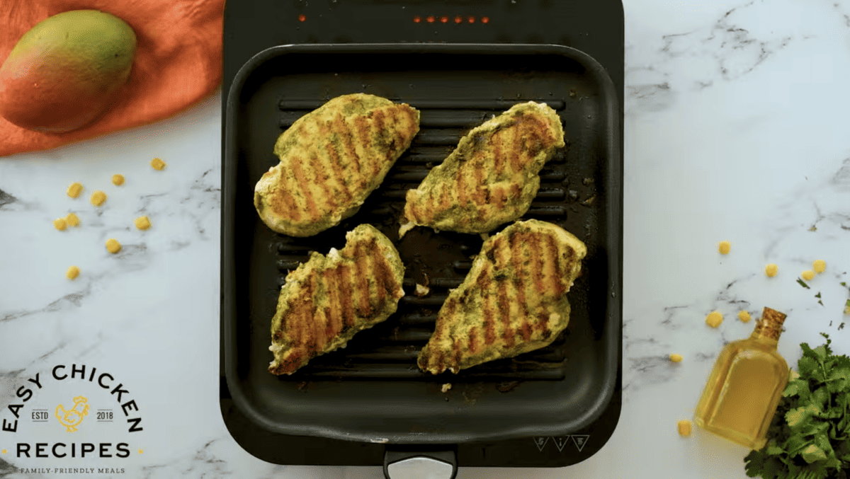 Grilled chicken breasts are on a small griddle. 