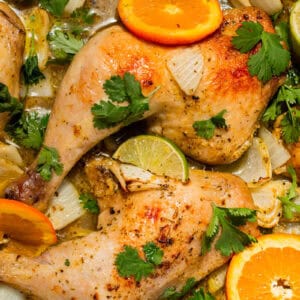 close up of cuban mojo chicken with citrus wedges.