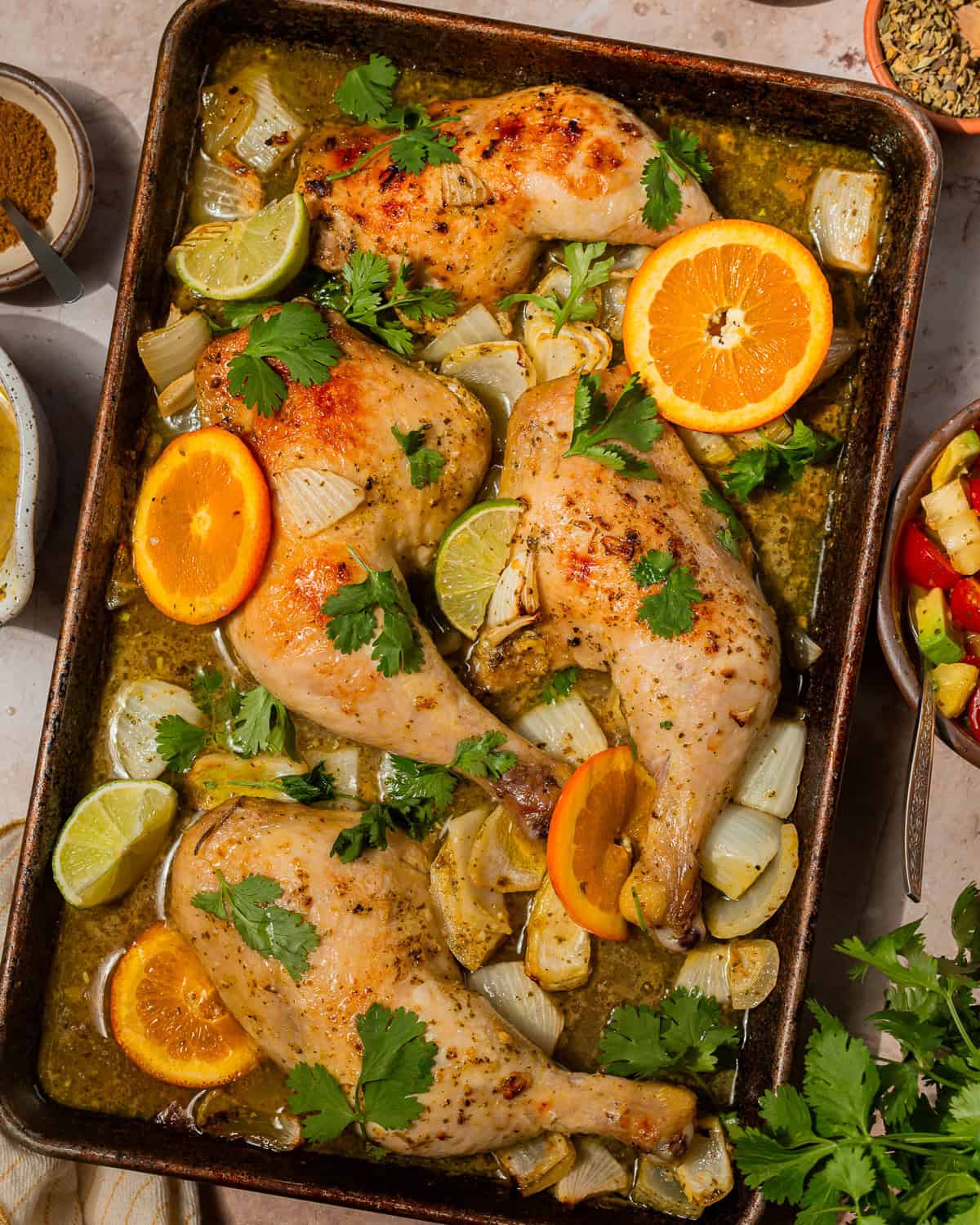 overhead view of cuban mojo chicken on a baking sheet with citrus wedges.