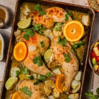 overhead view of cuban mojo chicken on a baking sheet with citrus wedges.