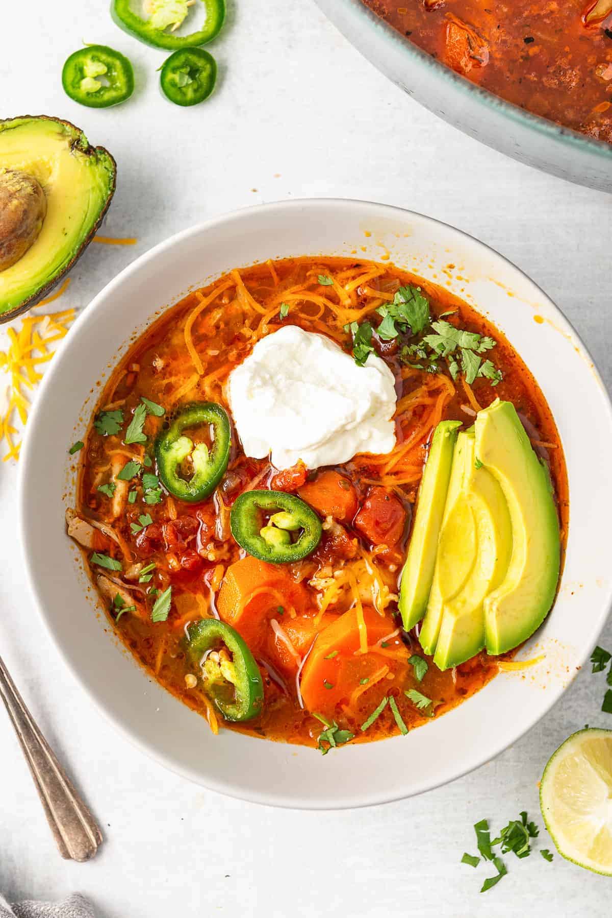 white bowl with spicy Mexican chicken soup garnished with avocado