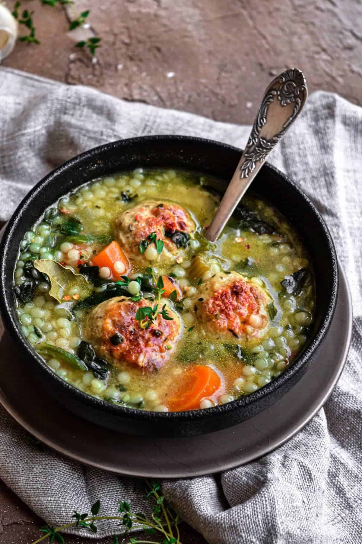 Italian Wedding Soup with chicken meatballs in a black bowl