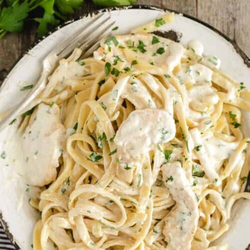 plated chicken alfredo with lots of white sauce.