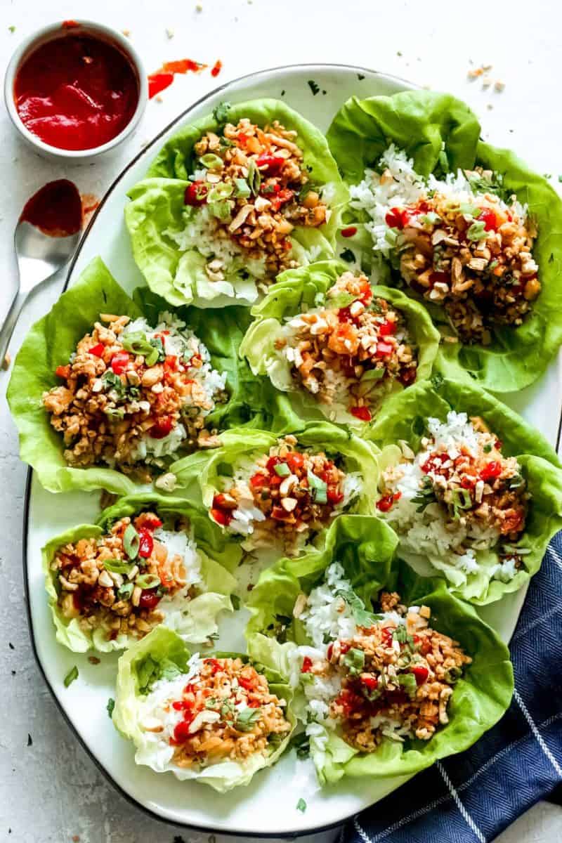 Chicken lettuce wraps with dipping sauce on a plate.