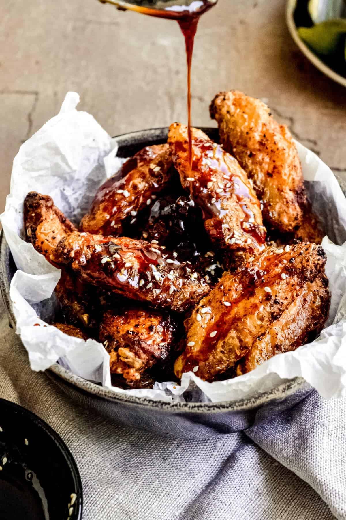 Sauce being poured on a basket of Soy Honey Glazed Chicken Wings