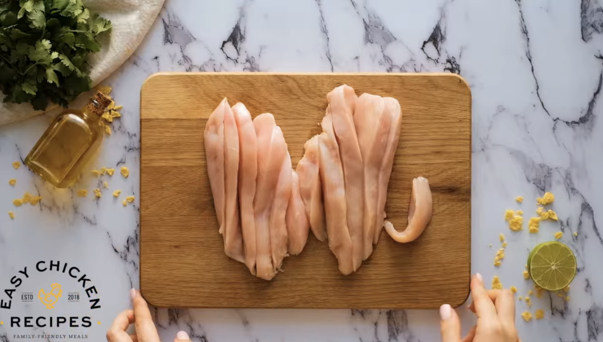 Chicken breasts are being cut into strips. 