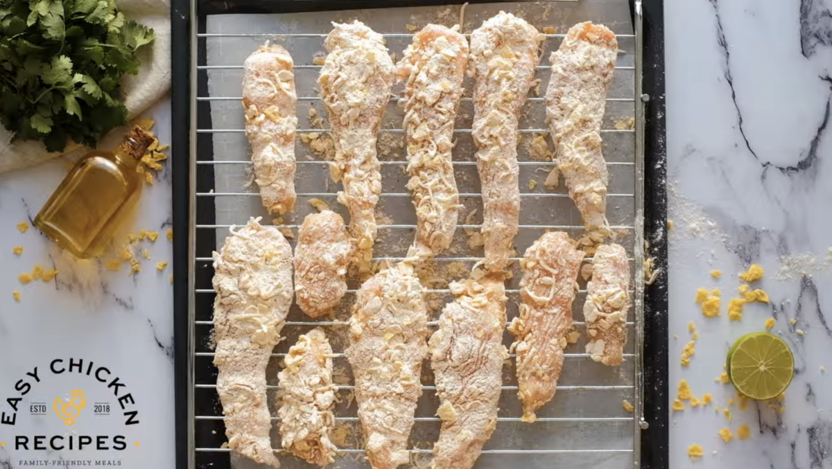 Uncooked chicken strips line a wire rack.