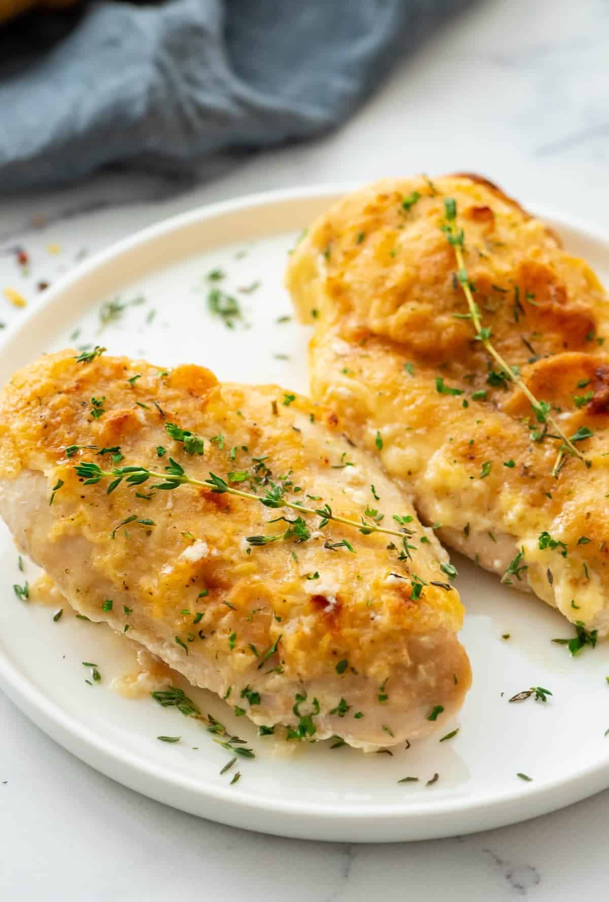 Two butter baked chicken breasts served on a white plate