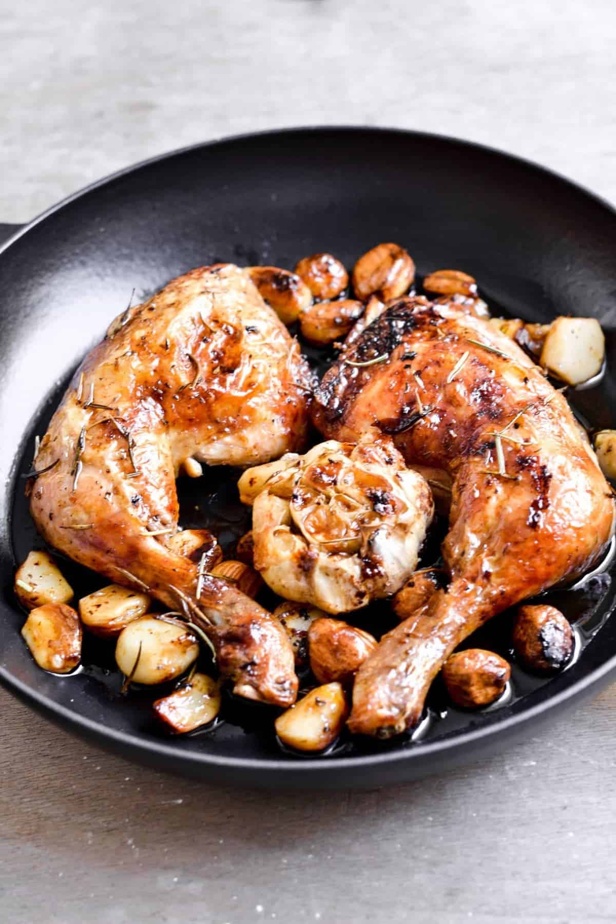 Chicken served with garlic cloves on a black plate