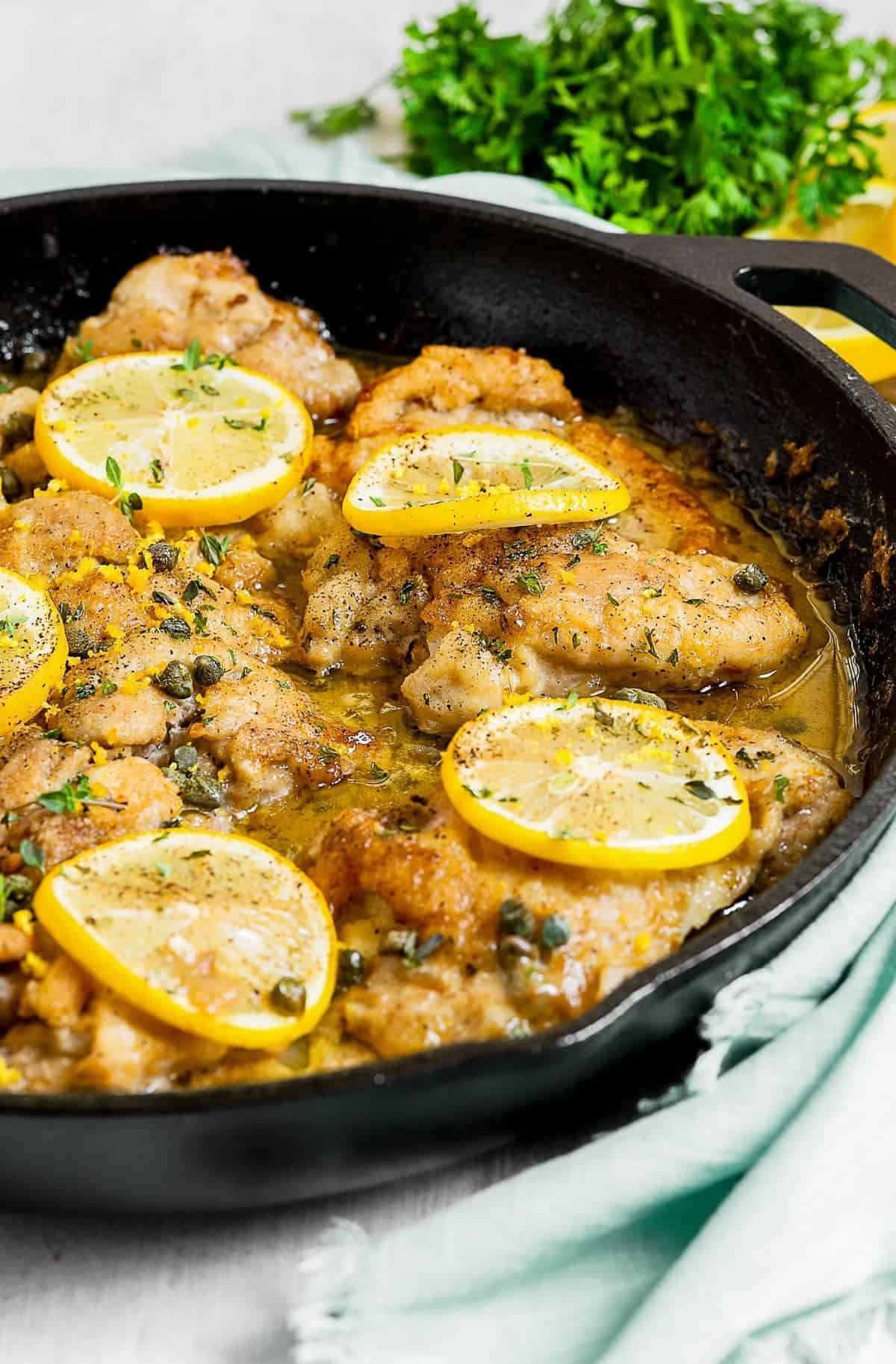 Lemon slices on top of cooked chicken in a skillet