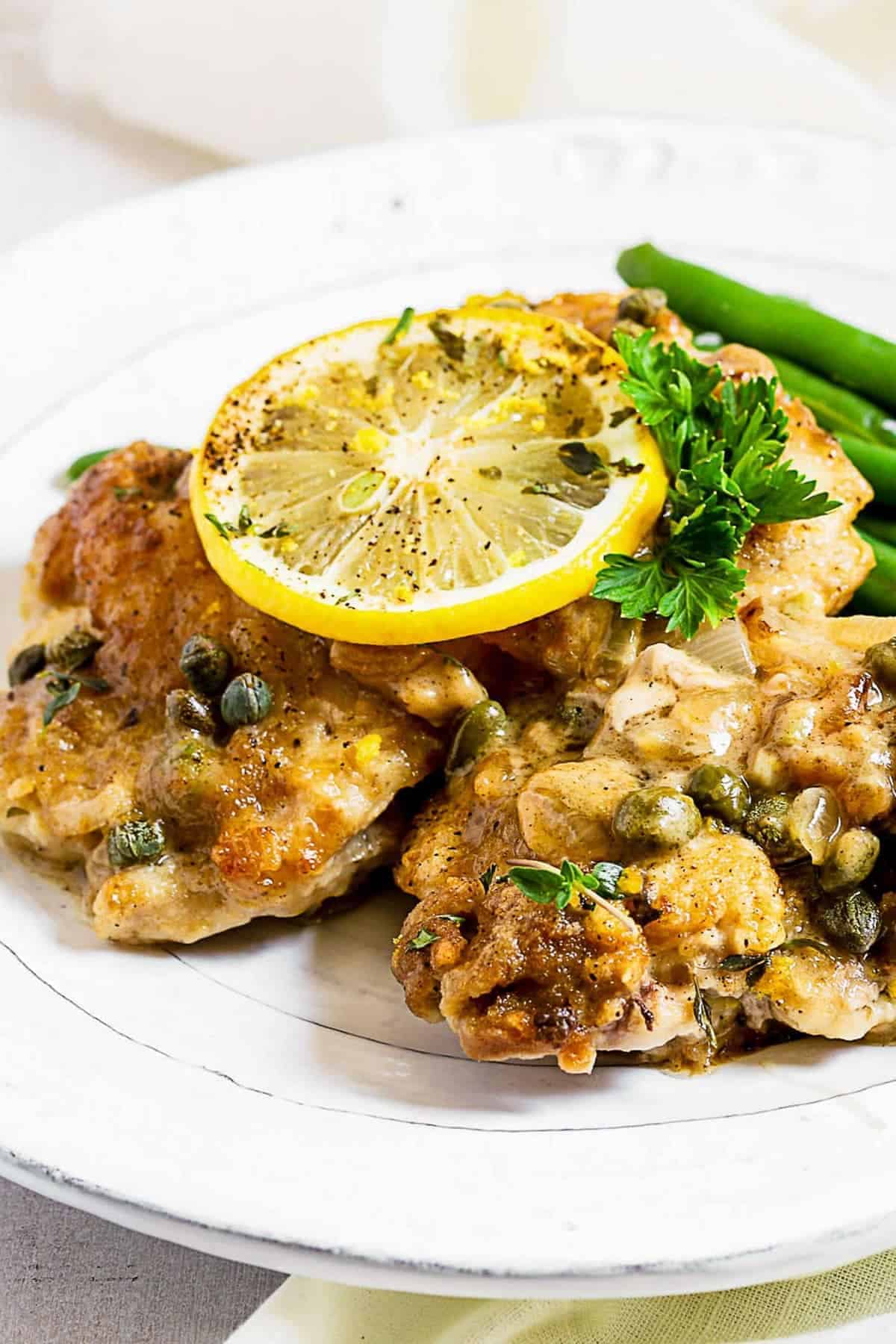 Close up of a slice of lemon on top of the chicken piccata