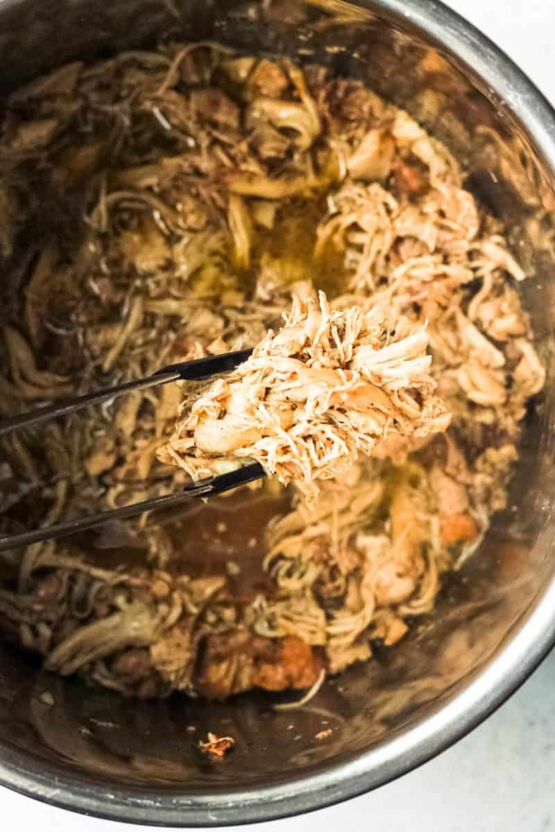 Instant Pot shredded chicken being stirred with a fork.
