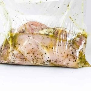 A person holding a plastic bag with sous vide chicken breast in it.