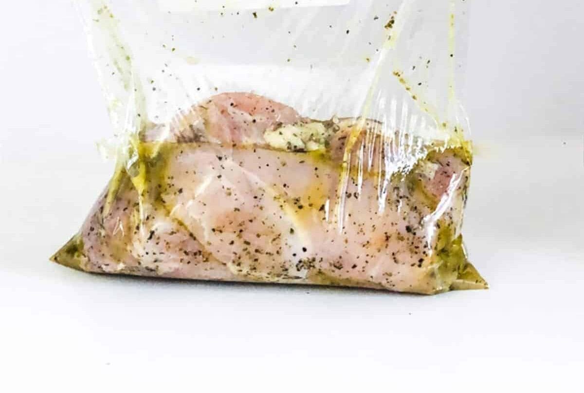 A person holding a plastic bag with sous vide chicken breast in it.