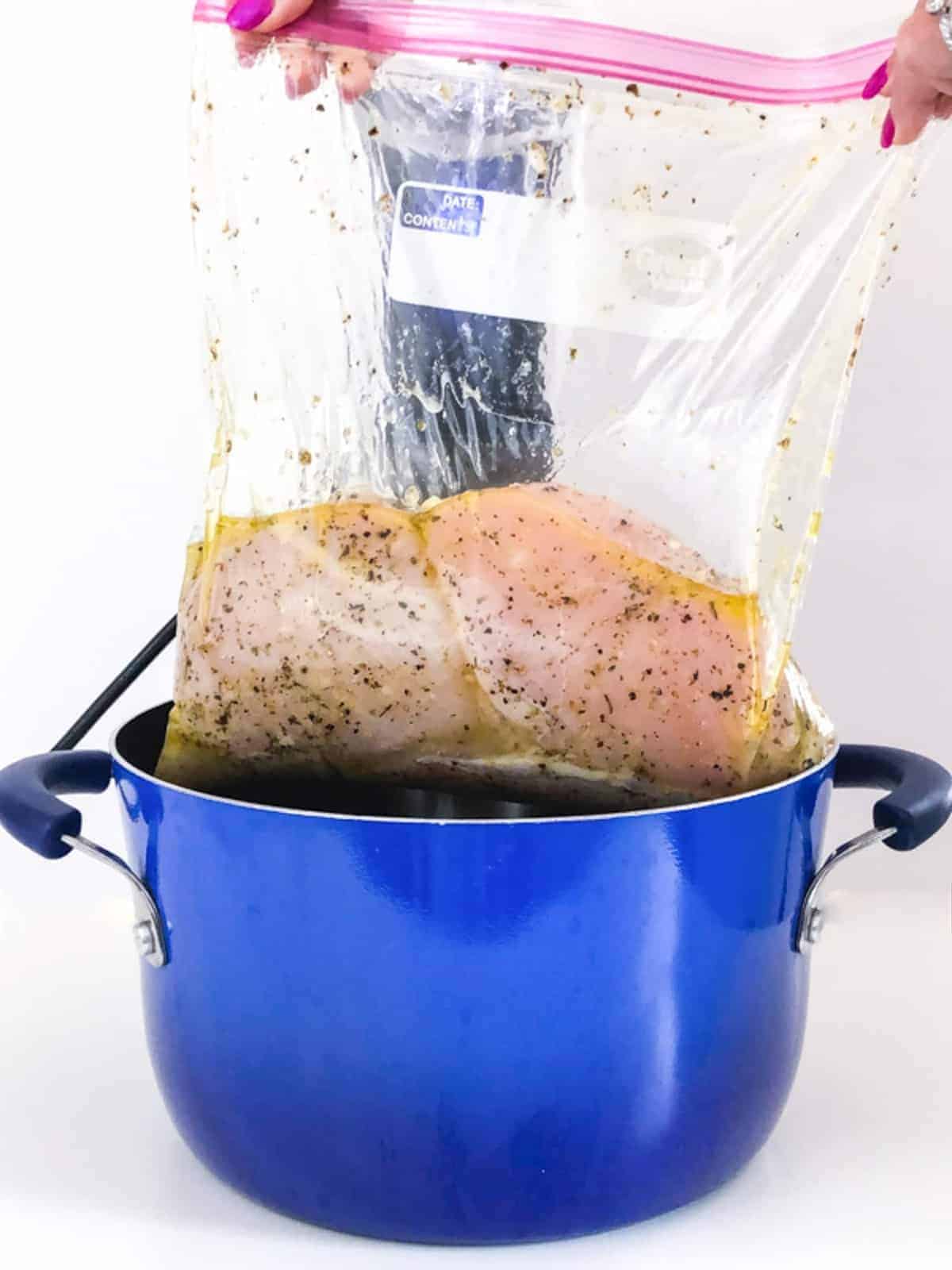 Chicken breast being placed into a pot 