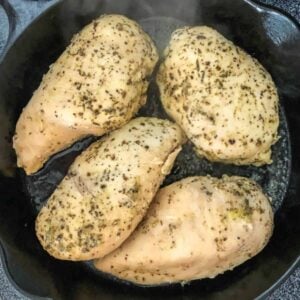 Sous vide chicken breasts cooked in a cast iron skillet on the stove.