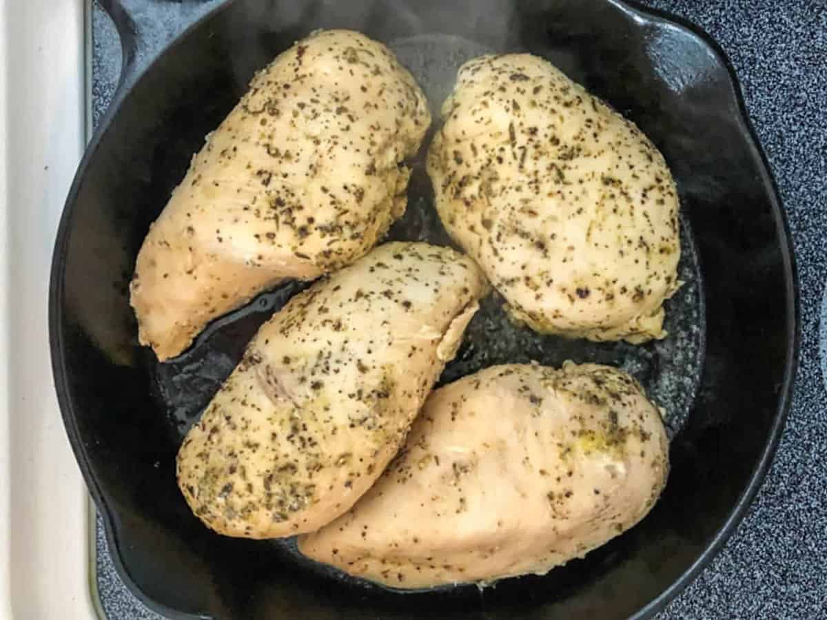 Sous vide chicken breasts cooked in a cast iron skillet on the stove.