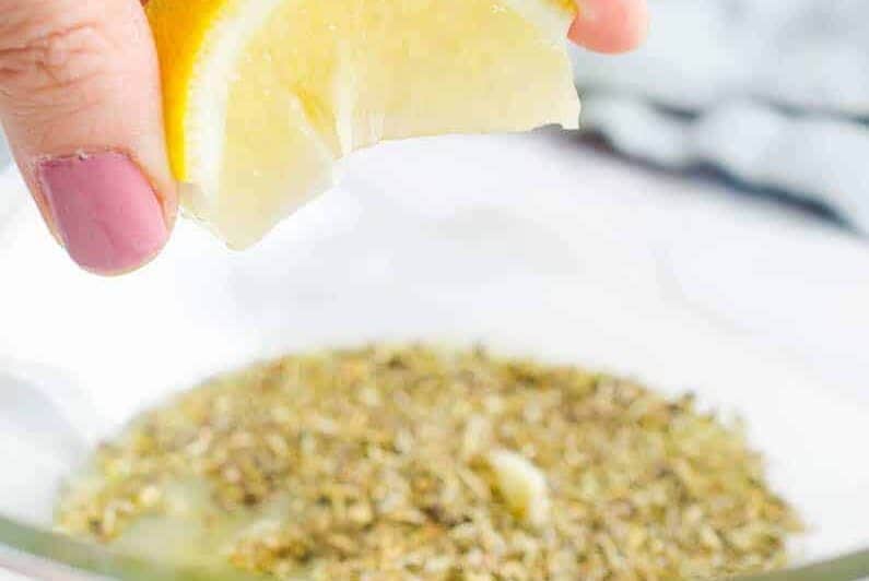 a person preparing sous vide chicken breast, squeezing lemon.