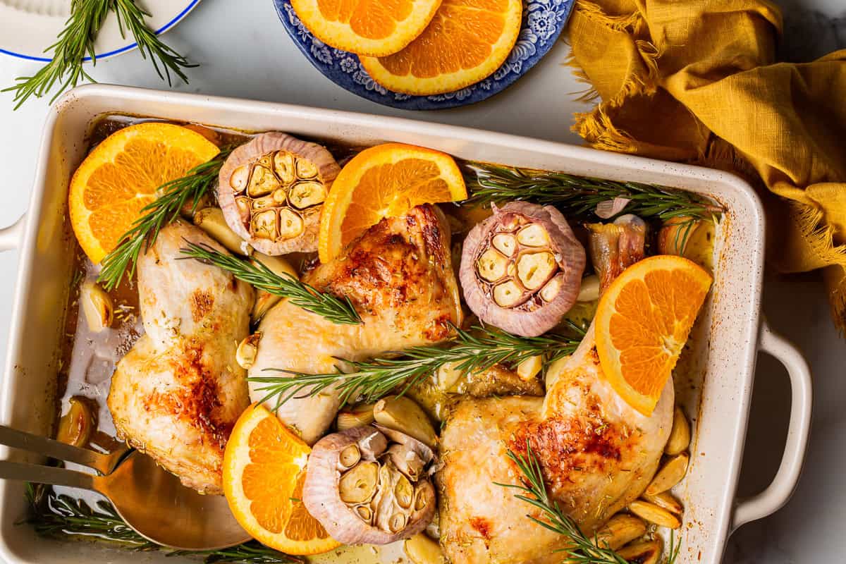 overhead view of chicken with 40 cloves of garlic in a baking dish.