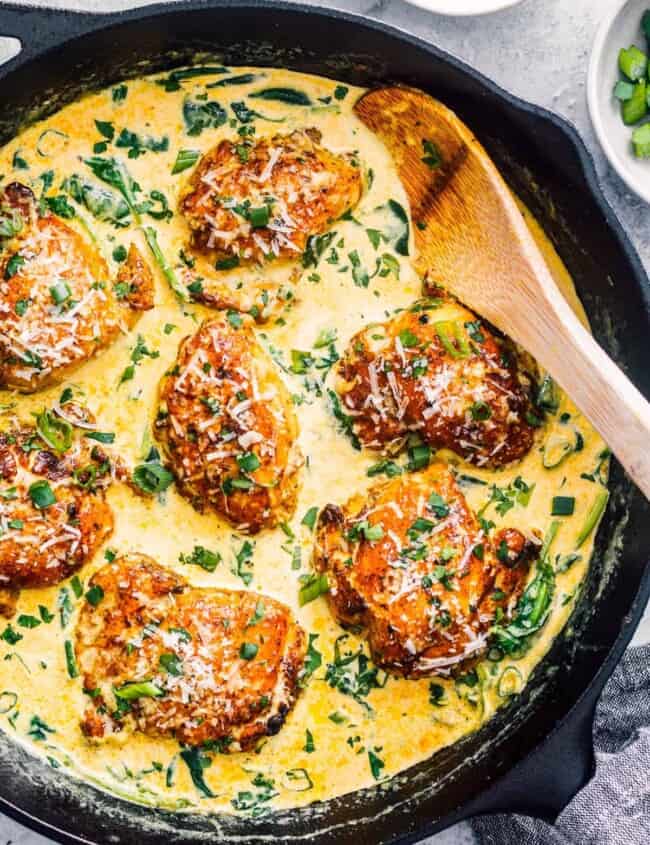 wooden spoon in cast iron skillet with chicken florentine