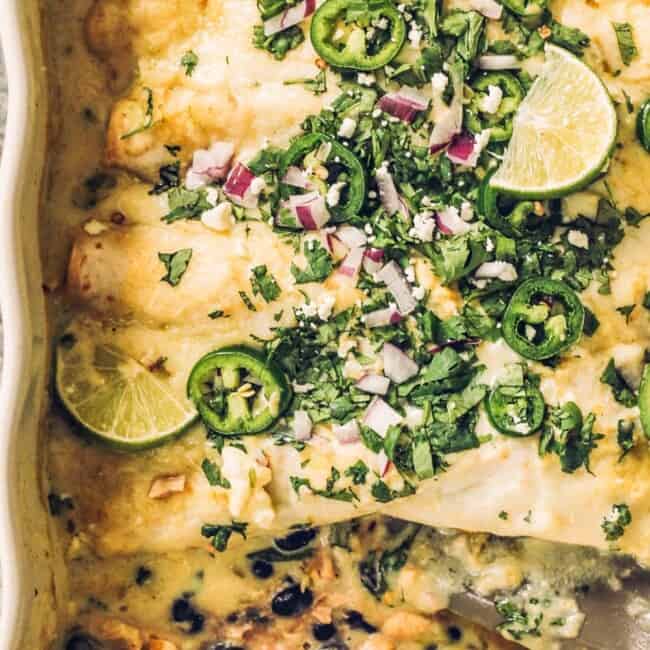 Black bean enchiladas topped with sour cream and baked in a dish.