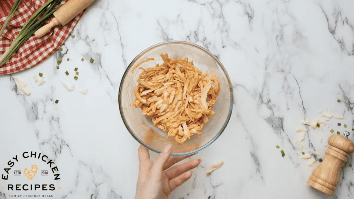 A bowl is filled with shredded buffalo chicken. 