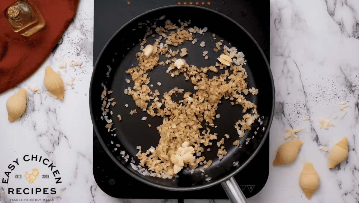 Onions and garlic are cooking in a pan.