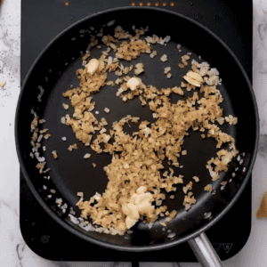 Onions and garlic are cooking in a pan.