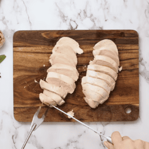 Chicken is being sliced on a cutting board.