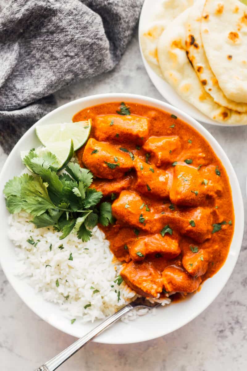 butter chicken with rice and cilantro in white bowl