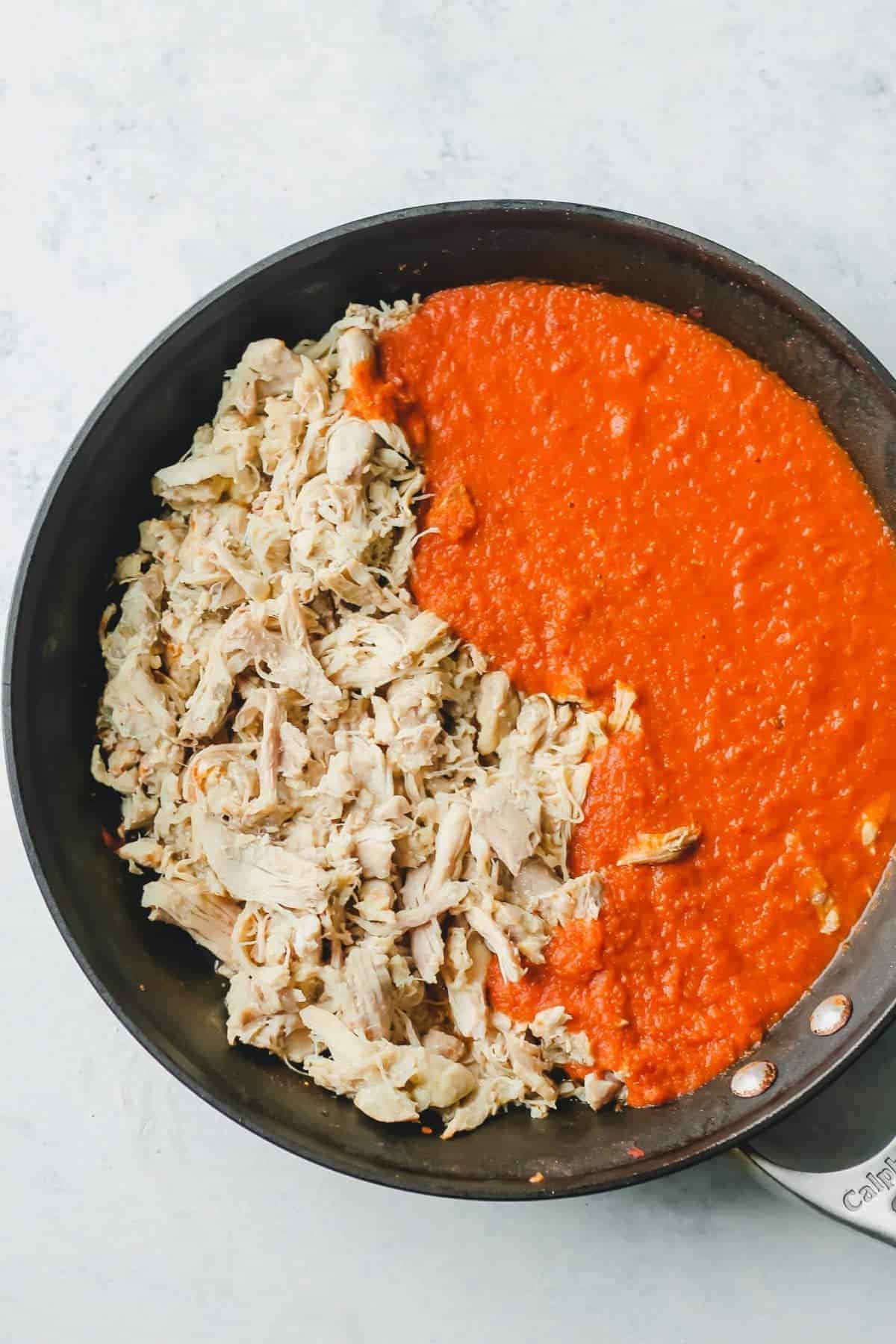 Shredded chicken and red sauce in a skillet
