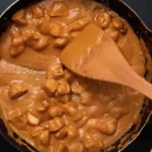 creamy butter chicken in a skillet with a wooden spatula.